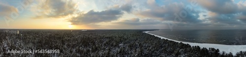 Sunrise over a calm bird's eye view of the sea and forest. Dramatic sunset on the Baltic sea in winter. photo