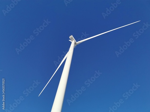Windmills or wind turbine on wind farm on blue sky background
