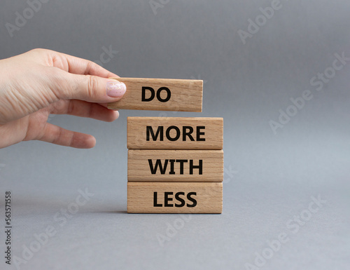 Do more with less symbol. Concept words Do more with less on wooden blocks. Beautiful grey background. Businessman hand. Business and Do more with less concept. Copy space.