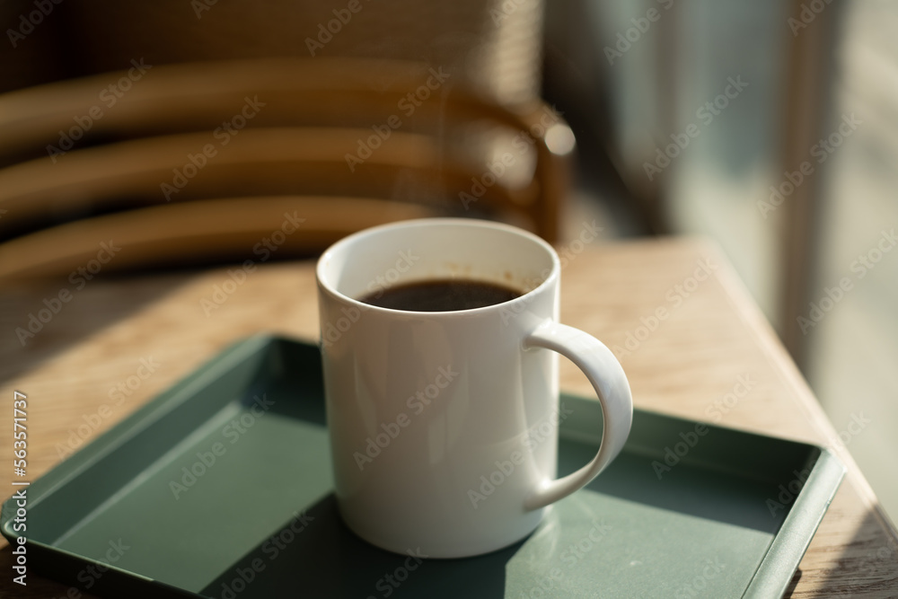 hot americano in a white cup on wood table with green tray