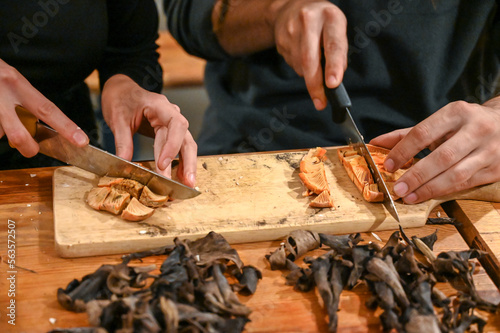 People cutting fresh wild mushrooms at wooden table. Preparing mushroom for lunch. Cutting mushroom. 