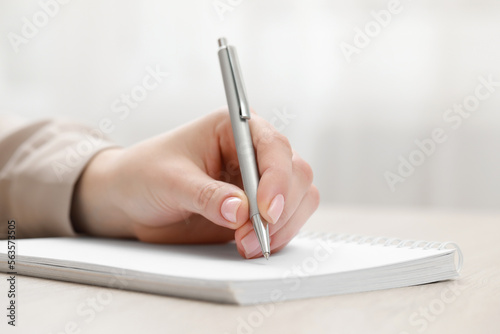 Woman writing in notebook at light table, closeup