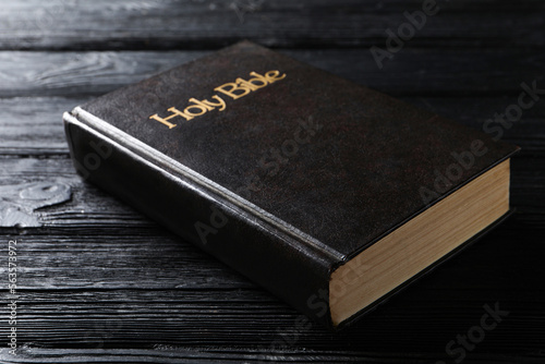 Bible with dark cover on black wooden table. Christian religious book
