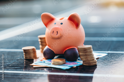 Piggybank on solar panel concept of money saved by using clean energy