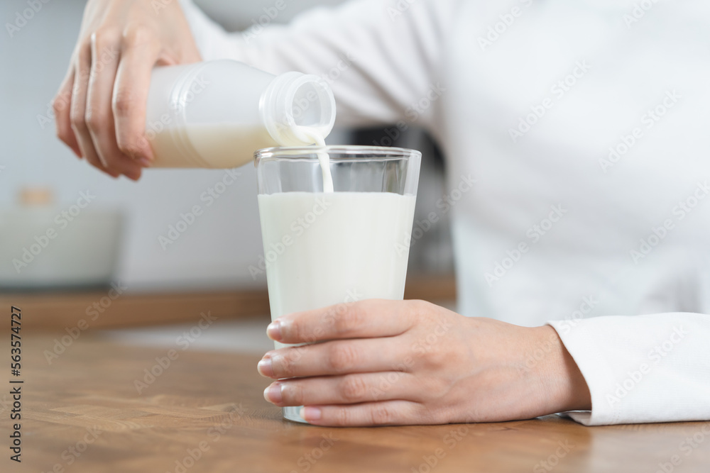 Close-up hands of Person pouring milk into a glass on the table Close-up hands of Person pouring milk into a glass on the table