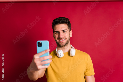 Young man with headphones and smartphone taking a selfie © The Attico Studio