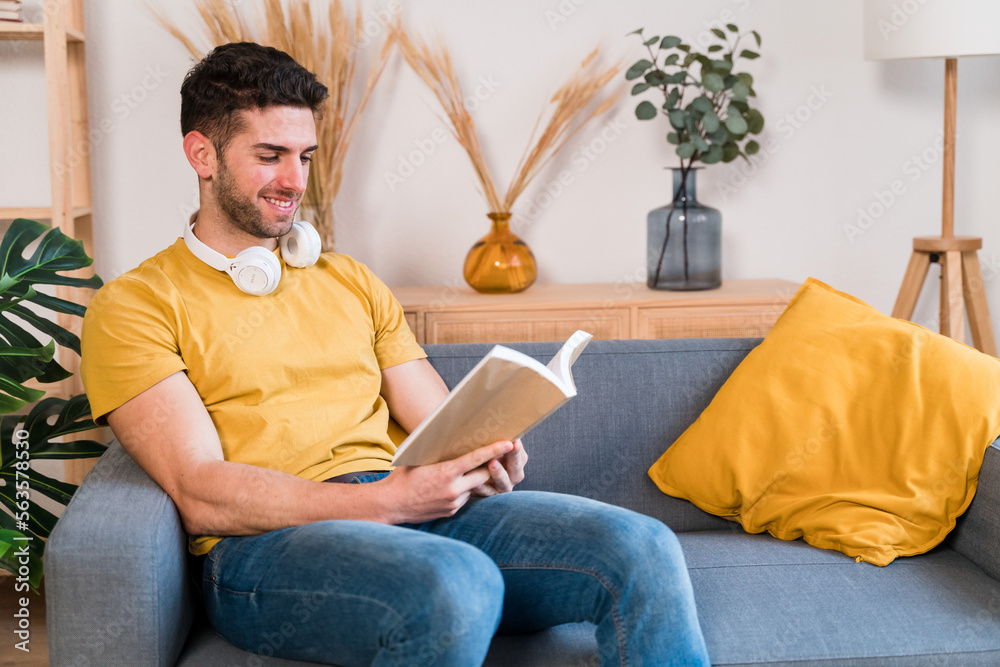 Cheerful man reading book on sofa