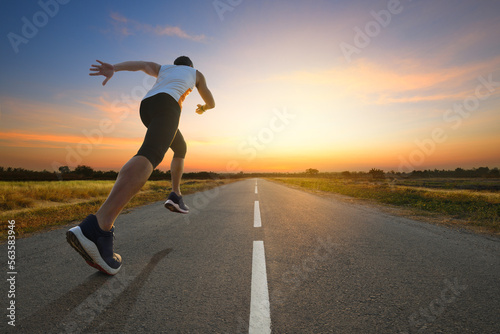 A man running on country road with sun dawn sky background... © Paitoon