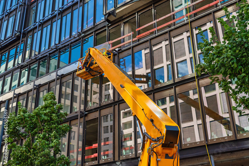 Construction worker using a cherry picker to mounting a Curtain wall facade of a contemporary office building.