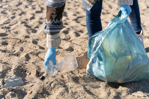 Hand of volunteer person collecting plastic bottle trash on the beach. Working for Ecology  © EFStock