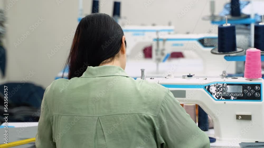 Woman tailor working at the sewing factory. Back view Woman tailor working at the sewing factory. Back view