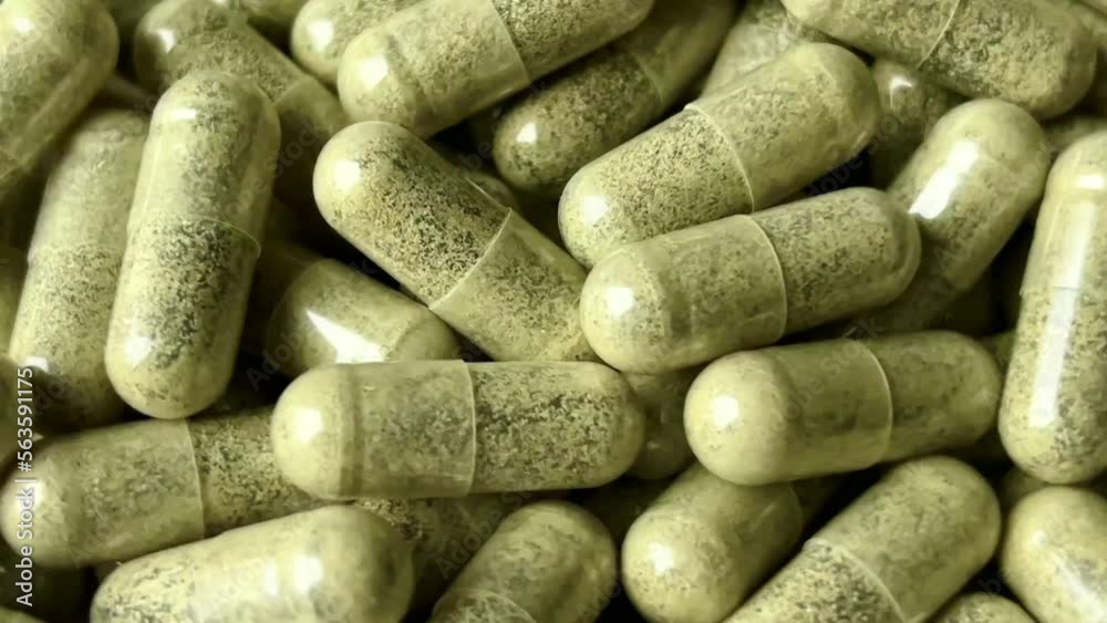 Green moringa oleifera or malunggay capsules. Spirulina capsule. Rotating background, close up.