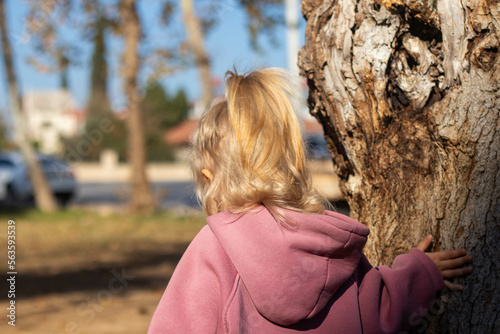 A little girl touching an old tree in the park © Roman