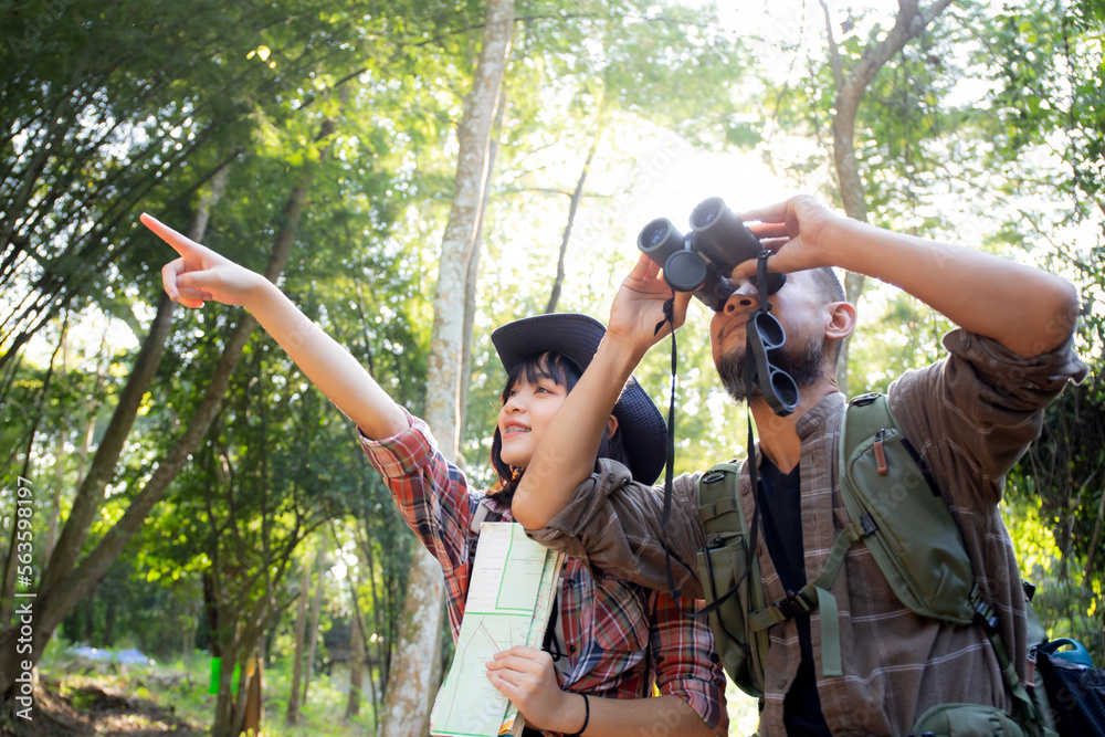 Fototapeta premium Family with father and daughter tourist backpack hiking doing activity while father looking binoculars in holiday together, man and teenager woman journey adventure trip and looking map.