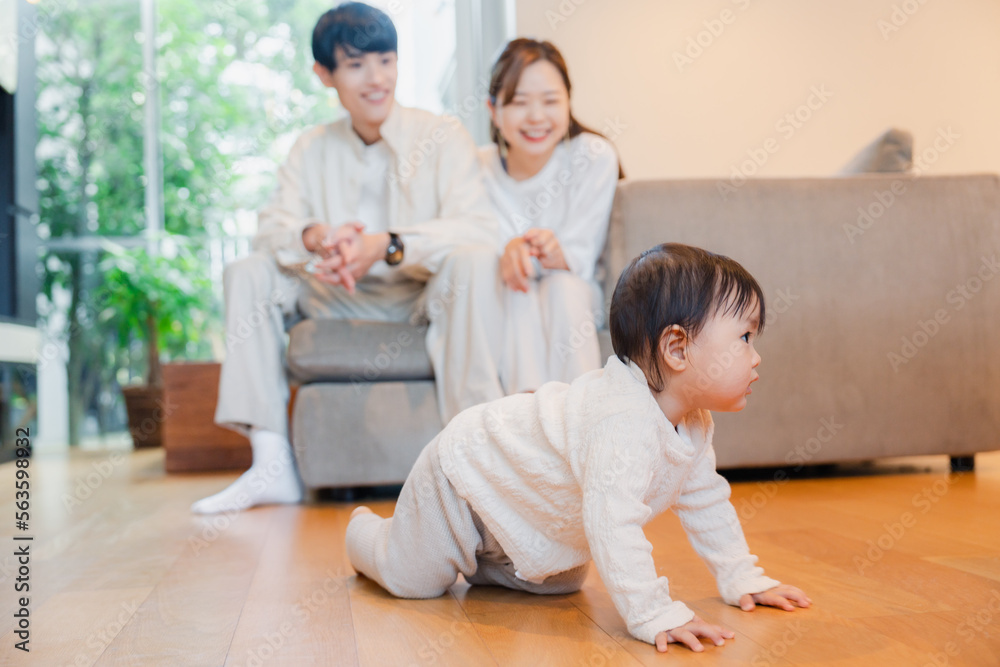ハイハイをする赤ちゃんと子供の成長を見守る両親 ハイハイをする赤ちゃんと子供の成長を見守る両親
