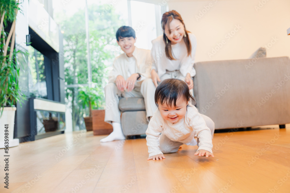 ハイハイをする赤ちゃんと子供の成長を見守る両親 ハイハイをする赤ちゃんと子供の成長を見守る両親