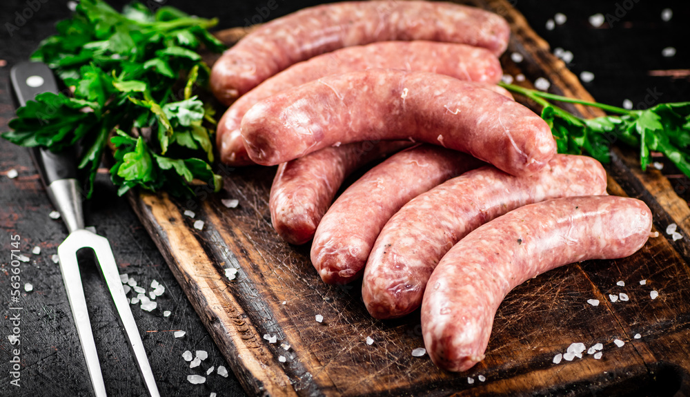 Raw sausages on a cutting board with parsley. 