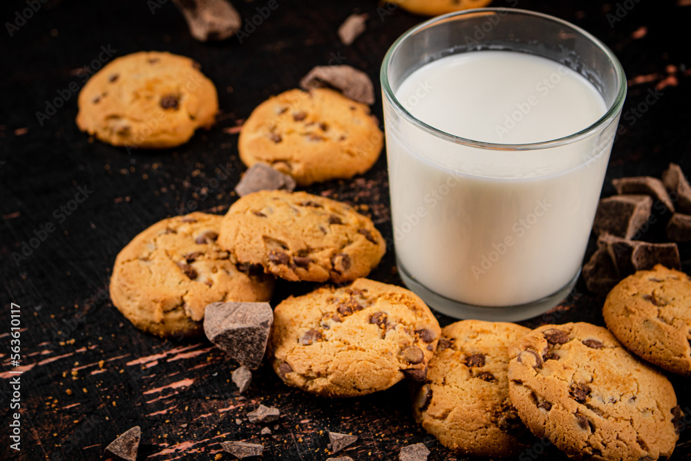 Homemade cookies with pieces of milk chocolate and a glass of milk. 
