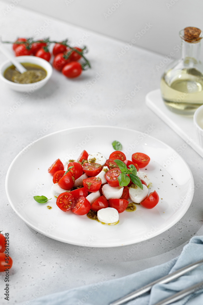 Caprese Salad with ripe tomatoes, mozzarella cheese, fresh basil, balsamic sauce, pesto on white plate. Healthy delicious diet salad. Caprese Salad with ripe tomatoes, mozzarella cheese, fresh basil, balsamic sauce, pesto on white plate. Healthy delicious diet salad.