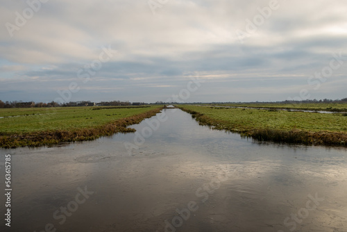Typical Dutch rural scenery showing the flat Netherlands. canal water is part of a flood management system for the polder which is land reclaimed from the sea and converted into arable farm fields