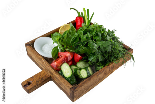 A variety of greens with fresh vegetables and salt in a wooden plate. Appetizing appetizer for lunch. Close-up. Isolated on white background.