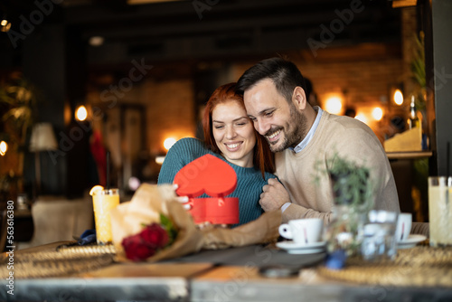 Valentines day couple sitting in favourite caffe  exchanging gifts in hart shape