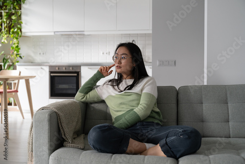 Photography Concentrated pensive Asian girl student looks away and touches face with hand when planning trip to college