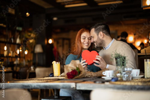 Valentines day couple sitting in favourite caffe  exchanging gifts in hart shape