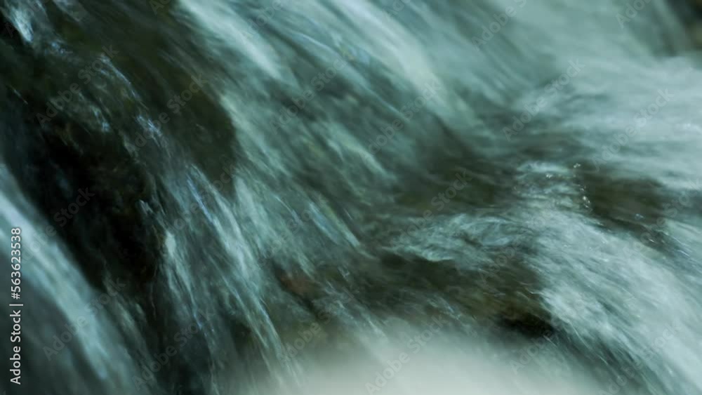Water flowing through a small river hits the rock and falls as a mini ...