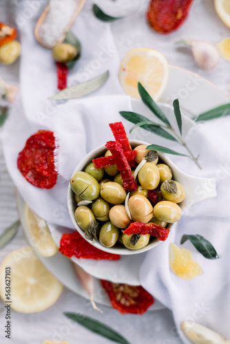 Various olives flavored with spices in white cup and glass jar. Green olives, black olives. Front and top shot on a white background