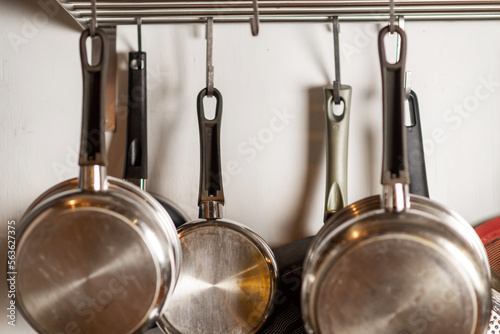 Pots and pans hang in the kitchen. Kitchen utensils, home interior.