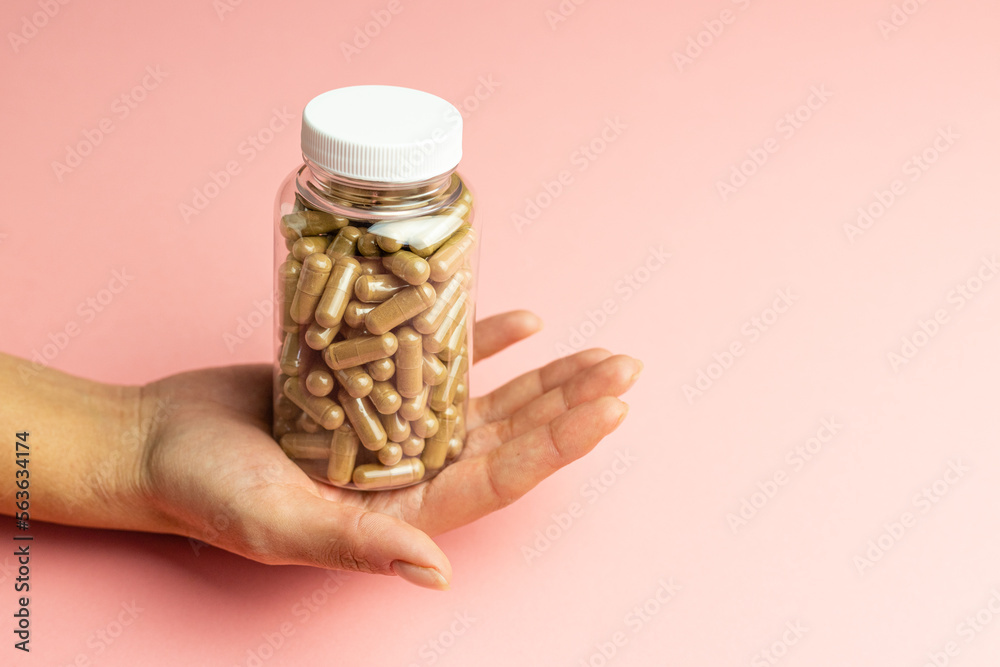 Obraz premium Hand holding a jar with ashwagandha capsules, immunity support, health care, body supplementation