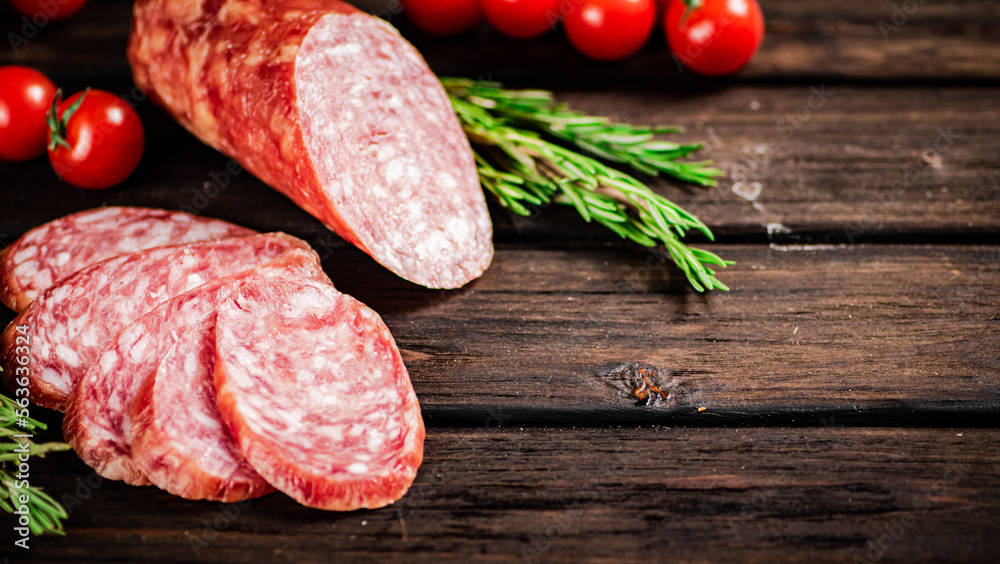 Pieces of delicious salami sausage with rosemary and tomatoes. Pieces of delicious salami sausage with rosemary and tomatoes.