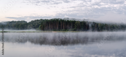 Mystical landscape. Rivers with a strip of forest in the fog at dawn.
