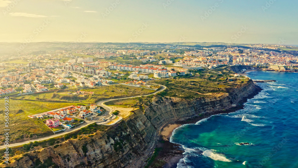 Drone view of a beautiful tourist town located on the shore of the Atlantic Ocean.  Panorama of the city from a drone with a  rocky ocean coastline during sunrise. Scenic summer  landscape  from drone
