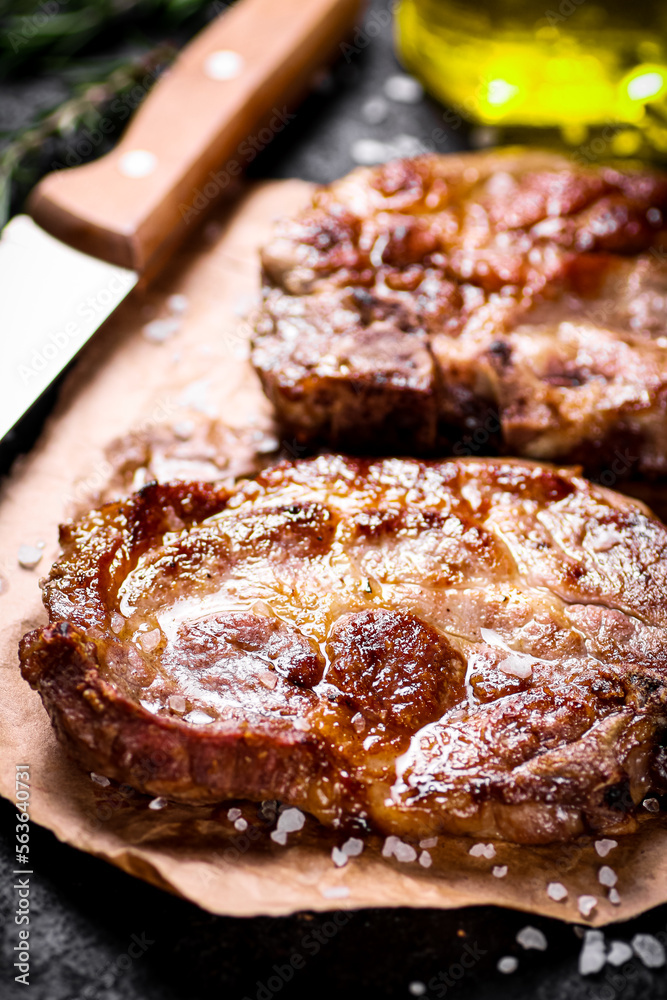 Grilled pork steak on paper on the table. Grilled pork steak on paper on the table.
