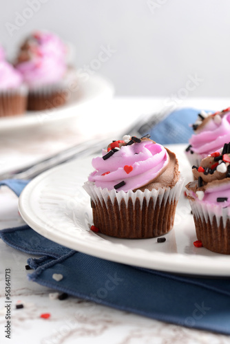 valentines day cupcakes with heart sprinkles and blue napkin