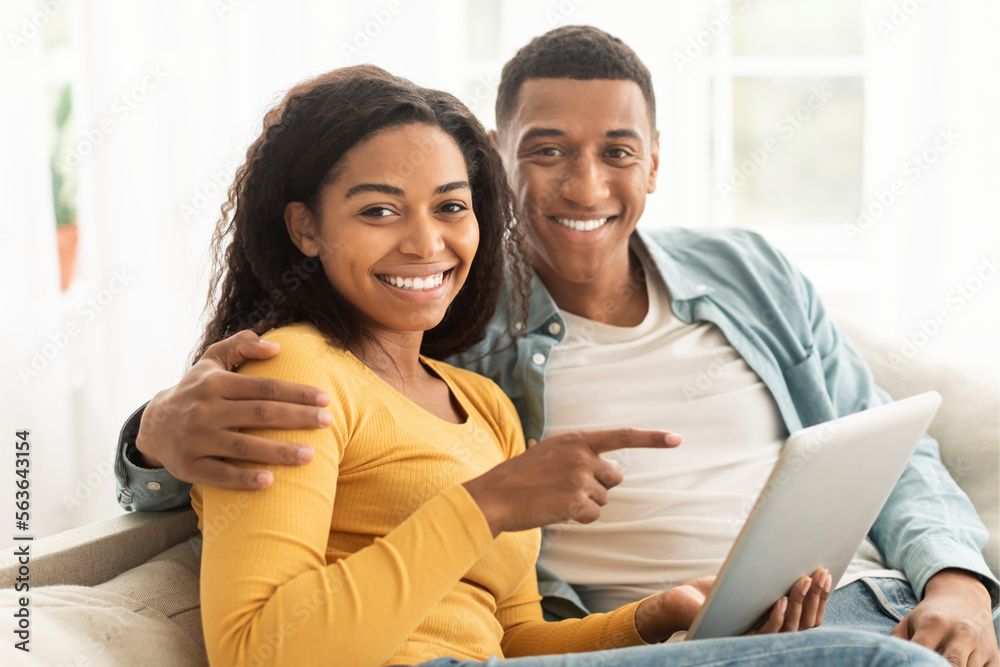 Happy young african american guy and lady point finger at phone, have video call, surfing in internet Happy young african american guy and lady point finger at phone, have video call, surfing in internet