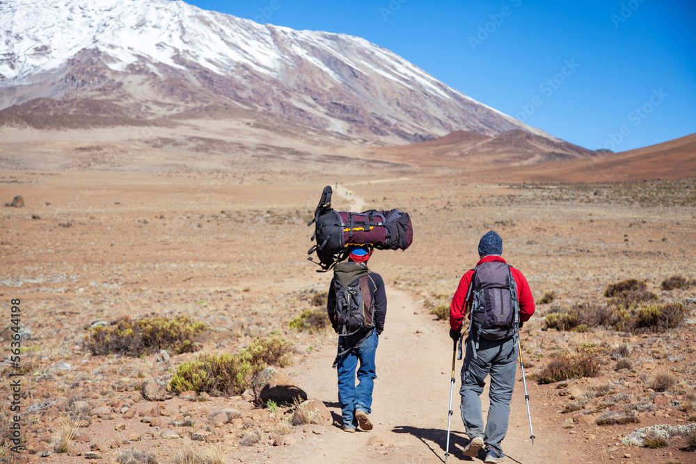 A porter carrying heavy load on his head on the way to Kilimanjaro mountain. Tanzania. A porter carrying heavy load on his head on the way to Kilimanjaro mountain. Tanzania.