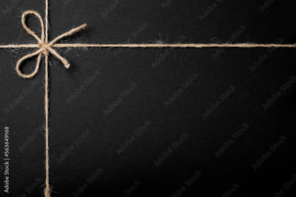 Jute string bow and framing lines on black paper texture Stock Photo ...