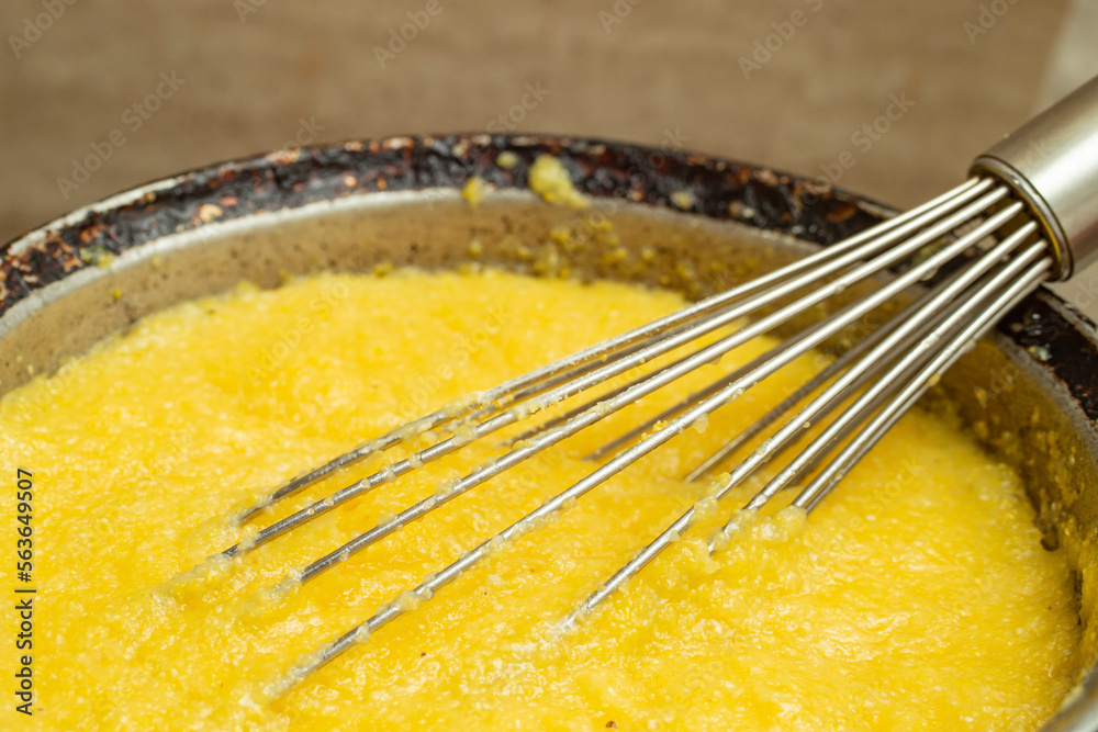 Boiling corn flour in a cast iron pot, making mamaliga, traditional