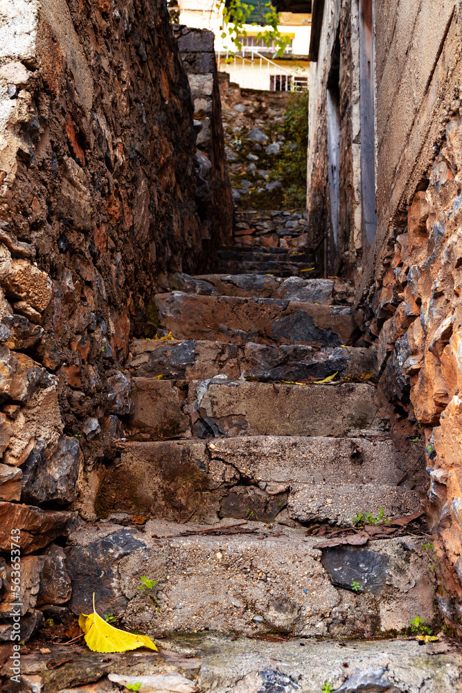 Old rock staircase with city view on background. Narrow stairway in the town. Selective focus. Blurred background.
