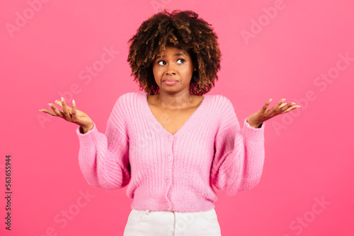 Insecure confused incompetent millennial african american curly lady in casual spreads her arms to sides