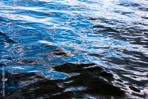 High shutter speed closeup shot of a wavy lake water flow. Deep blue black colors of the lake water surface.