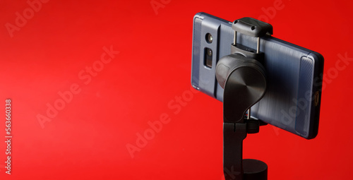 Modern smartphone on gimbal selfie stick for photo-video filming on a mobile phone. Gadgets for blogging, live streaming, journalism and videoconferencing. Copy space. Selective focus.