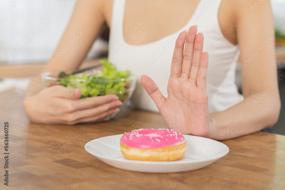 Diet, Dieting asian young woman or girl use hand push out, deny sweet donut and choose tomato, mix salad vegetables, eat food for good healthy, health when hungry. Close up female weight loss person. Diet, Dieting asian young woman or girl use hand push out, deny sweet donut and choose tomato, mix salad vegetables, eat food for good healthy, health when hungry. Close up female weight loss person.