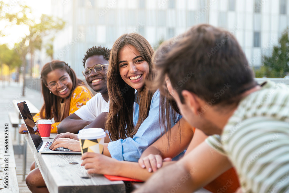 Group of five friends having fun together - students talking laughing and enjoying their time - focus on girl - education concept
