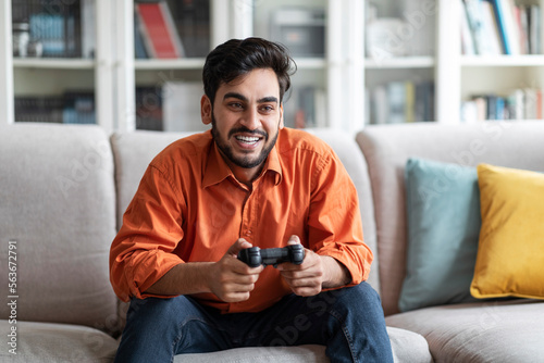 Handsome young middle eastern man playing video games at home