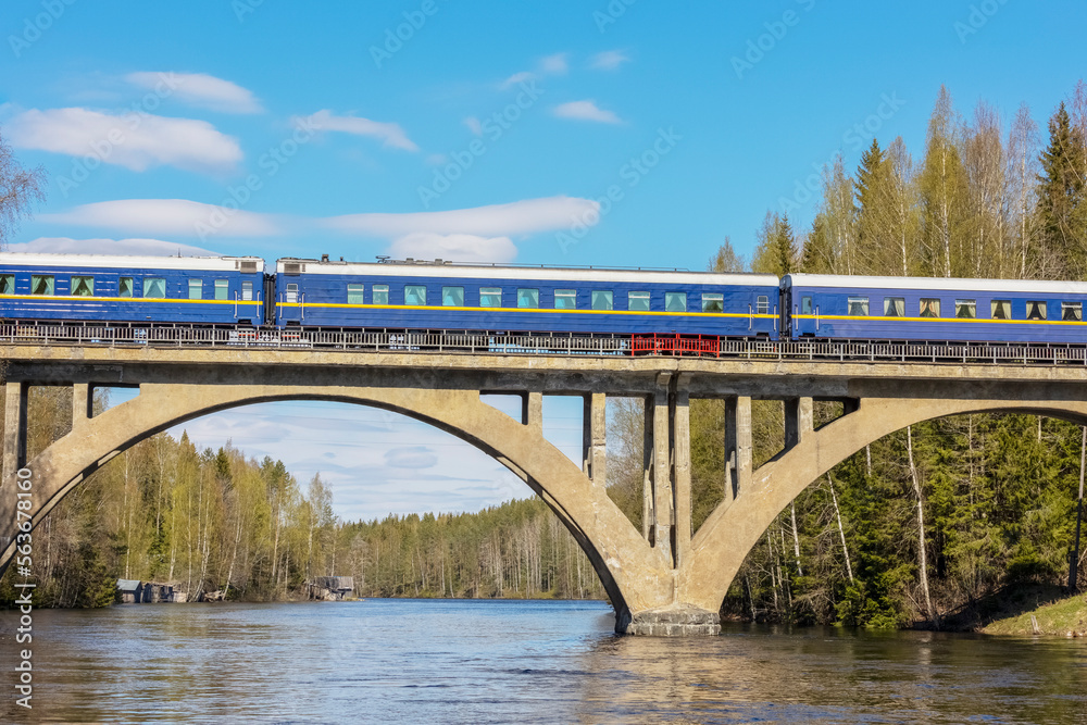 Fototapeta premium passenger train on a high old railway bridge over the river