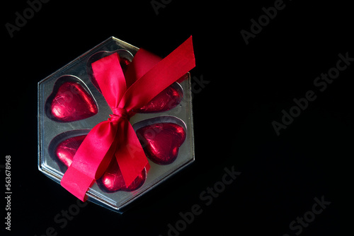 present on a black background, heart-shaped bombomes with a red ribbon . background for valentine's day mother's day
